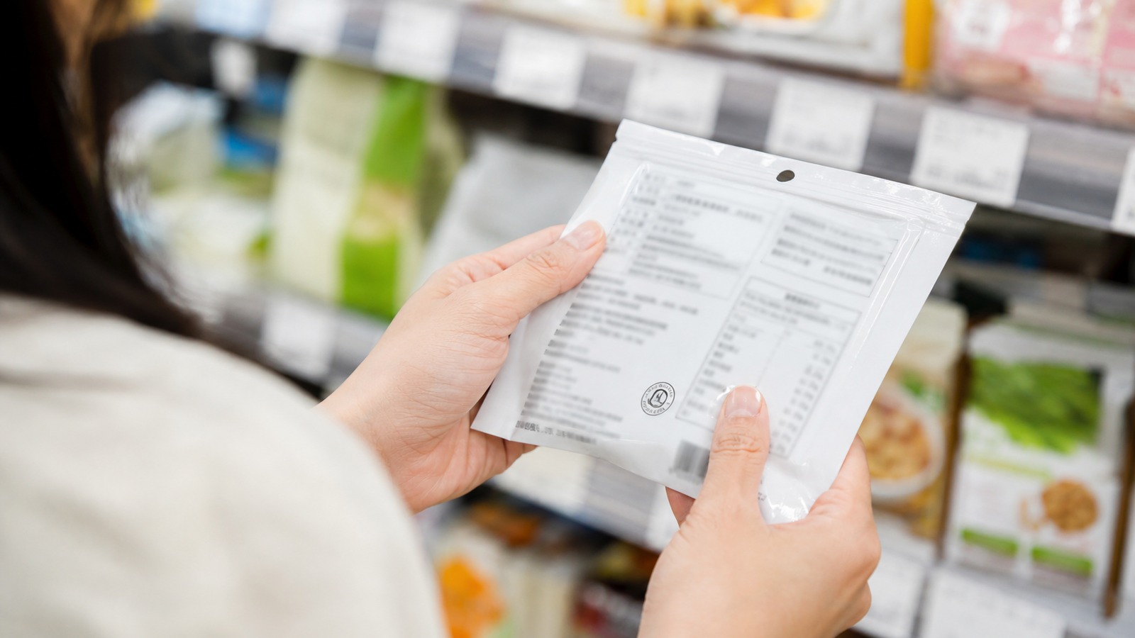 食品パッケージのマークと栄養成分表示を丁寧に確認する日本人の手元