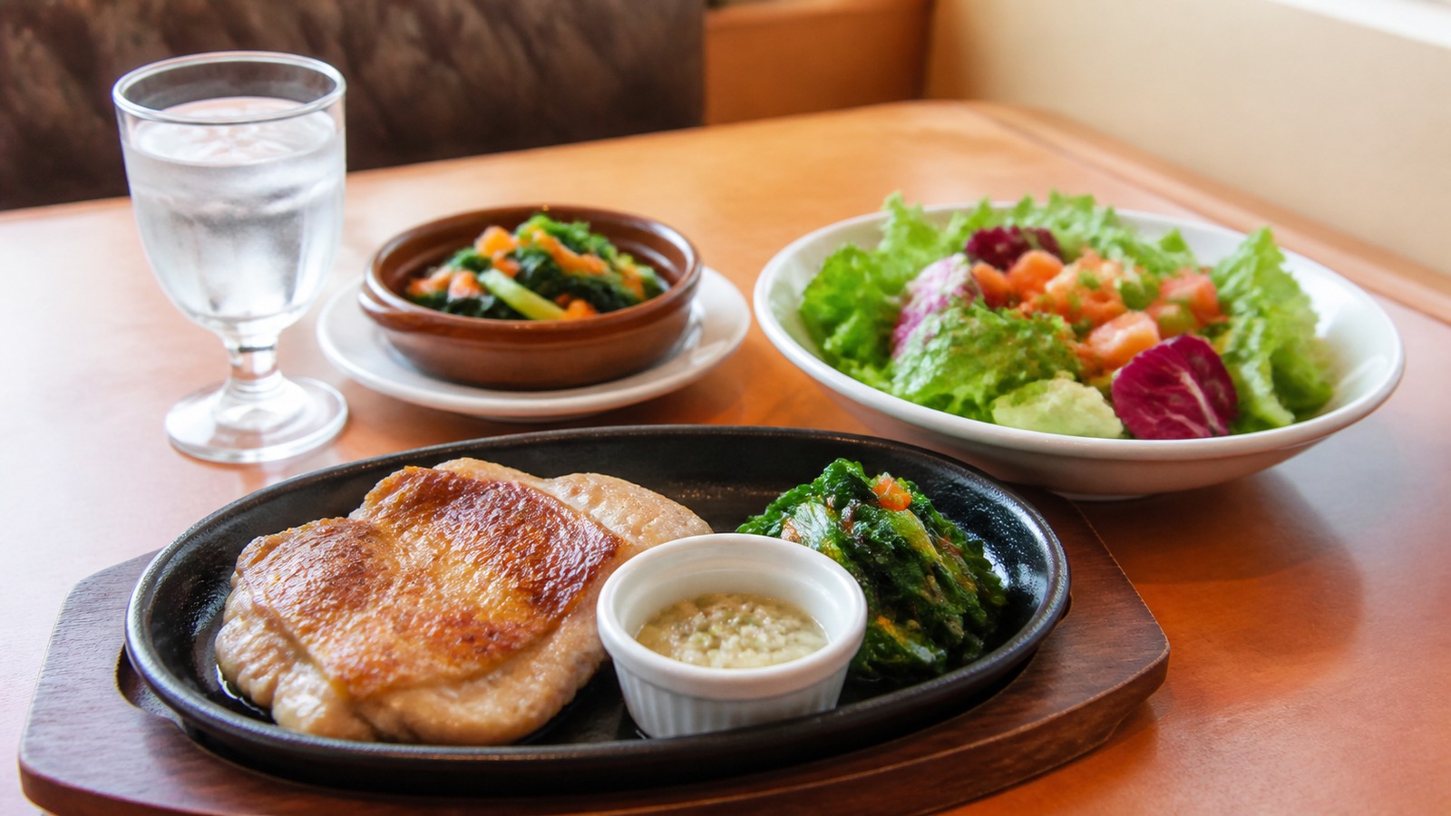 サイゼリヤ風のテーブルにサラダ、チキン、野菜料理、水が並び、糖質制限中の外食メニュー選びをイメージできる横長写真